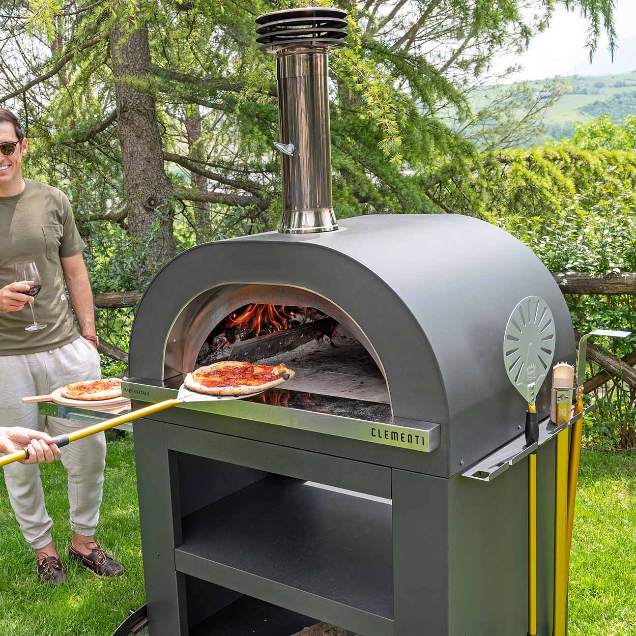 pizza being added to wood fired oven in garden setting