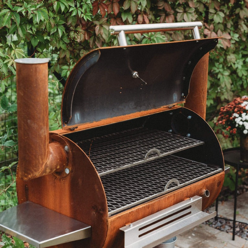 Corten steel BBQ smoker with lid open showing interior