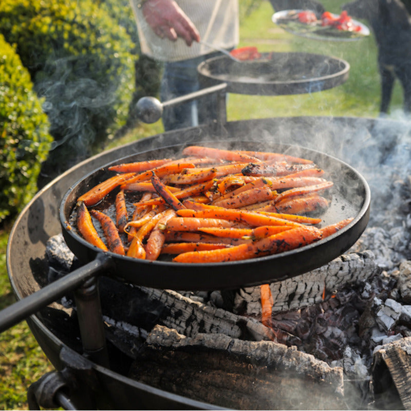 Firepits UK Plain Jane 90 with Three Swing Arm BBQ Racks with close up of carrots cooking